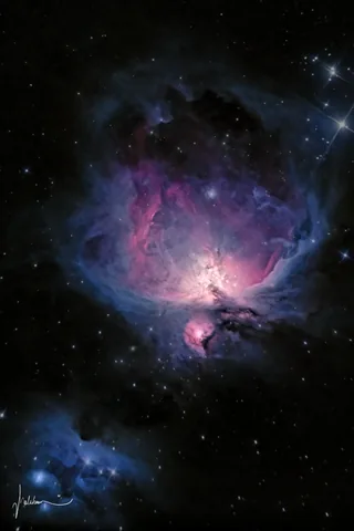 The Orion Nebula glowing pink and blue against a dark star field.